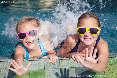 Image of Two happy children  playing on the swimming pool at the day time