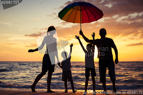 Image of Silhouette of happy family who playing on the beach at the sunse