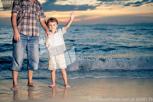 Image of Father and son playing on the beach at the sunset time.