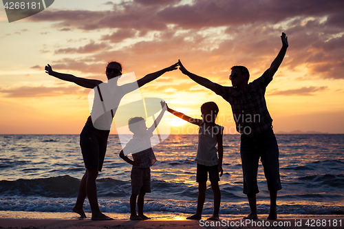 Image of Silhouette of happy family who playing on the beach at the sunse