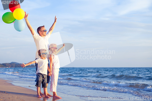 Image of Father and children playing on the beach at the day time.