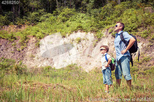 Image of Father and son standing near the pond at the day time.