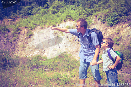 Image of Father and son standing near the pond at the day time.