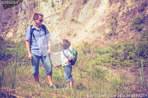 Image of Father and son standing near the pond at the day time.