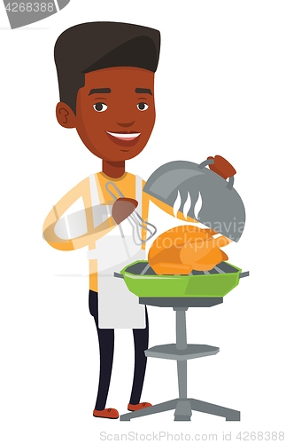 Image of Man cooking chicken on barbecue grill.