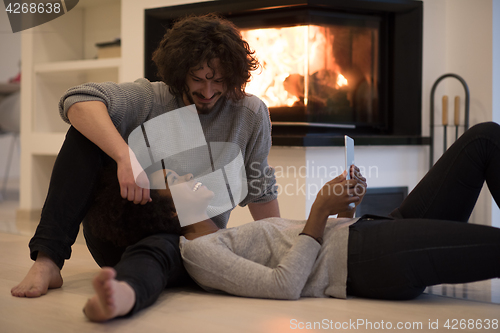 Image of multiethnic couple using tablet computer on the floor