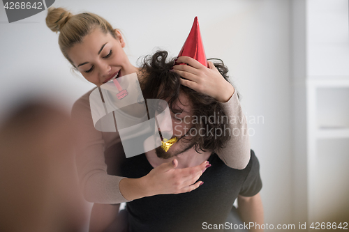 Image of couple in party hats blowing in whistle