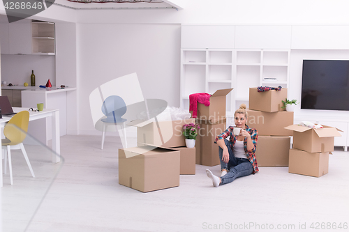 Image of woman with many cardboard boxes sitting on floor