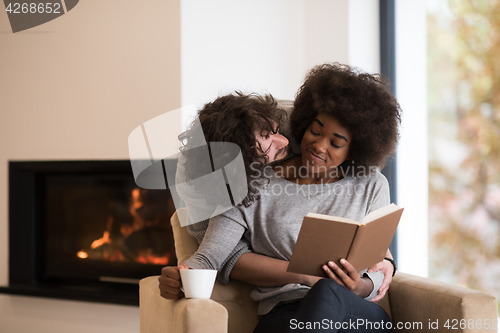 Image of multiethnic couple hugging in front of fireplace