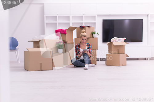 Image of woman with many cardboard boxes sitting on floor