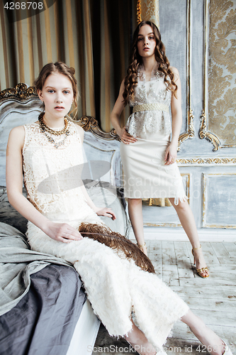 Image of two pretty twin sister blond curly hairstyle girl in luxury house interior together, rich young people concept 