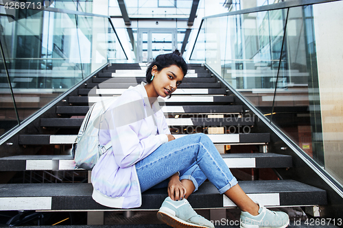 Image of young cute indian girl at university building sitting on stairs 