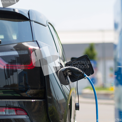 Image of Power supply plugged into an electric car being charged.