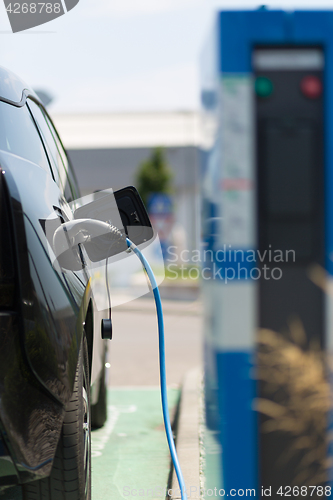 Image of Power supply plugged into an electric car being charged.