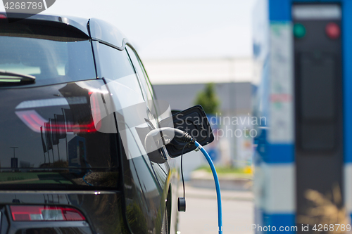 Image of Power supply plugged into an electric car being charged.