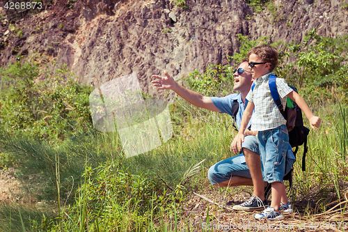 Image of Father and son siting near the pond at the day time.