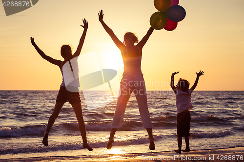 Image of Mother and children playing on the beach at the sunset time.