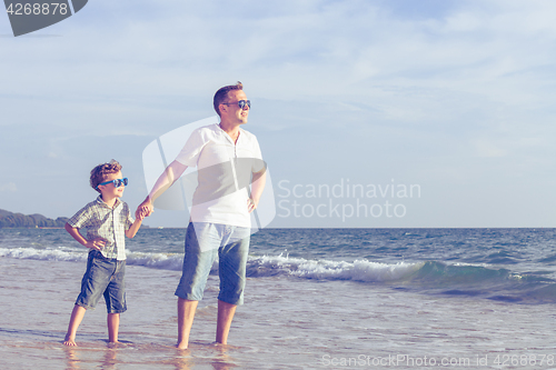 Image of Father and son playing on the beach at the day time.