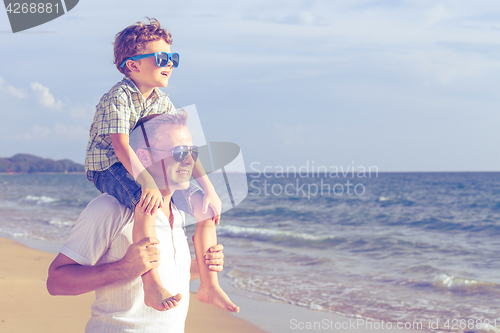 Image of Father and son playing on the beach at the day time.