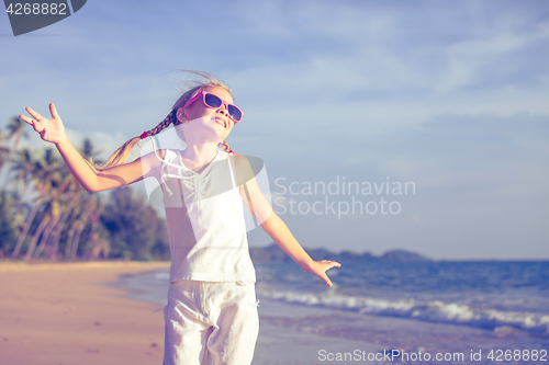 Image of Little girl  dancing on the beach at the day time.