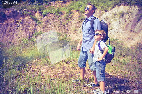 Image of Father and son standing near the pond at the day time. 