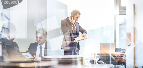 Image of Businessman talking on a mobile phone on corporate office.