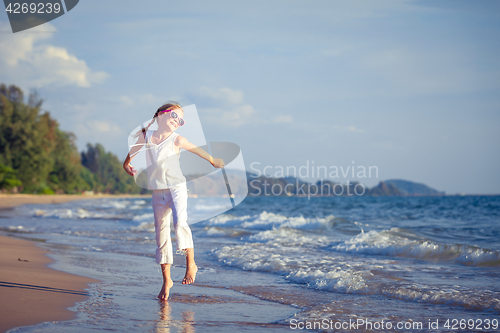 Image of Little girl  dancing on the beach at the day time.