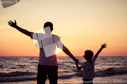 Image of Father and son playing on the beach at the sunset time.