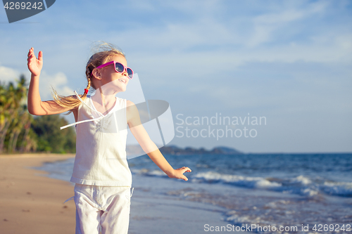 Image of Little girl  dancing on the beach at the day time. 