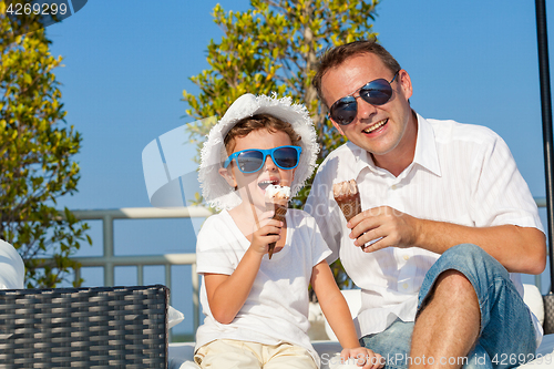 Image of Father and son relaxing near a swimming pool  at the day time.