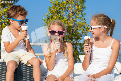 Image of three happy children eating ice cream near swimming pool at the 