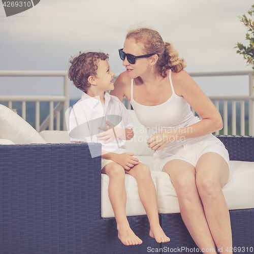 Image of Mother and son relaxing near a swimming pool  at the day time.