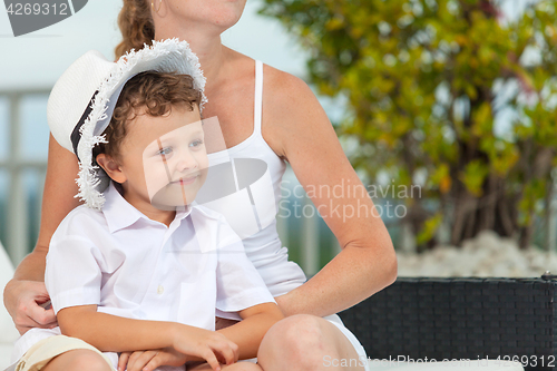 Image of Mother and son relaxing near a swimming pool  at the day time.