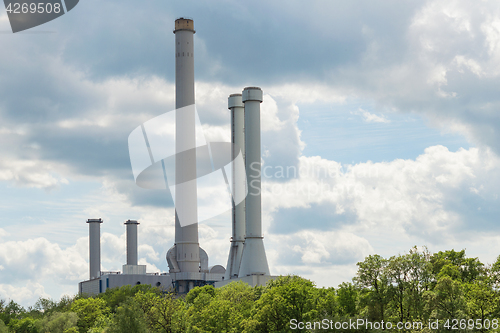 Image of Industrial smokestack over green forest trees