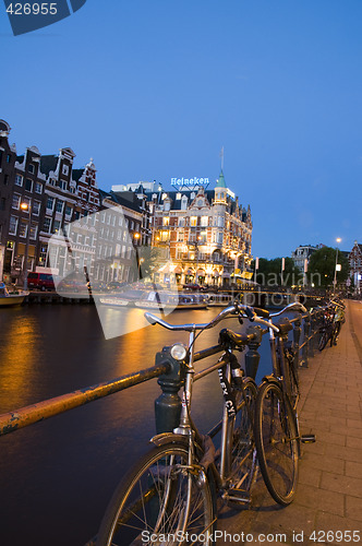 Image of editorial amsterdam night canal scen with bicycles and boats