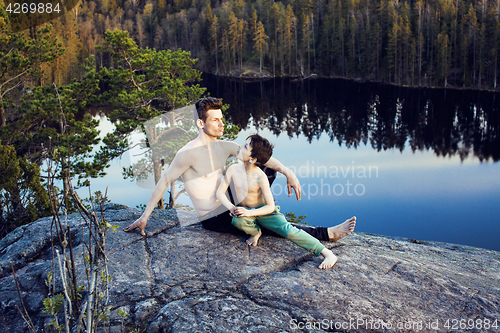 Image of middle age man with little cute son doing sport yoga on the top of the mountain together, happy family lifestyle people outdoor, summer wild nature for training