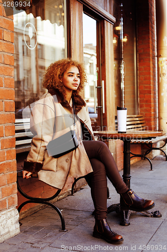Image of young pretty african american women drinking coffee outside in c