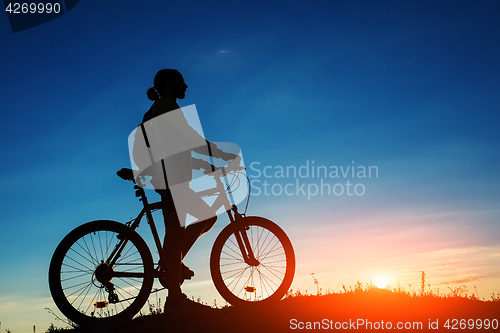 Image of Silhouette of cyclist and a bike on sky background