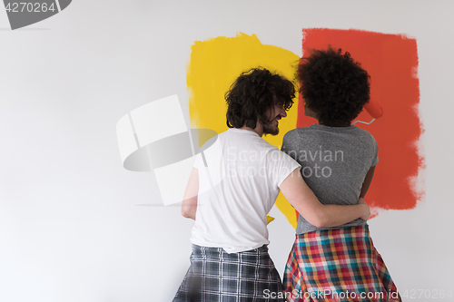 Image of multiethnic couple painting interior wall