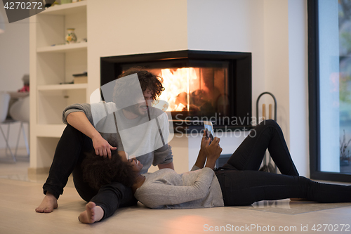 Image of multiethnic couple using tablet computer on the floor