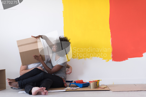 Image of young multiethnic couple playing with cardboard boxes