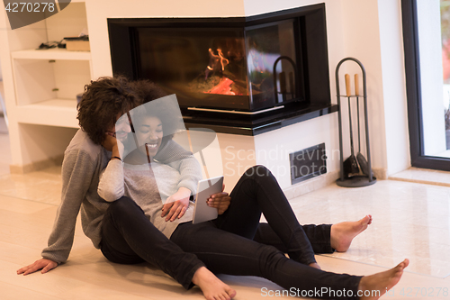 Image of multiethnic couple using tablet computer on the floor