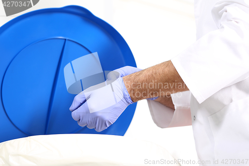 Image of Medical waste, surgeon dropping the gloves in a special container for waste 