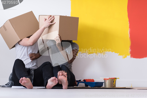 Image of young multiethnic couple playing with cardboard boxes