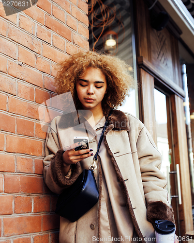 Image of young pretty african american women drinking coffee outside in c