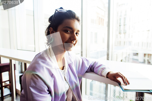 Image of young cute hipster girl student sitting in cafe with notebook re