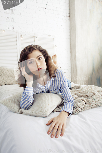 Image of young pretty brunette woman in her bedroom sitting at window, happy smiling lifestyle people concept 