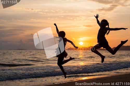 Image of Two happy girls jumping on the beach 