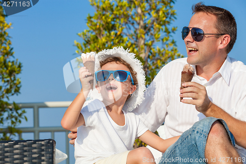 Image of Father and son relaxing near a swimming pool  at the day time.