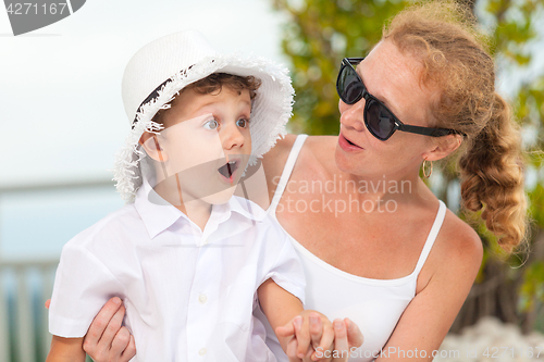 Image of Mother and son relaxing near a swimming pool  at the day time.